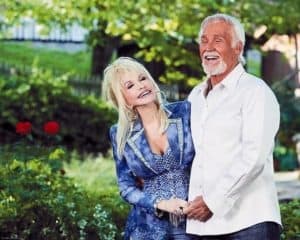 Dolly Parton and Kenny Rogers smiling and holding hands