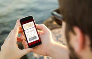 man with beard and sunglasses buying concert ticket on phone